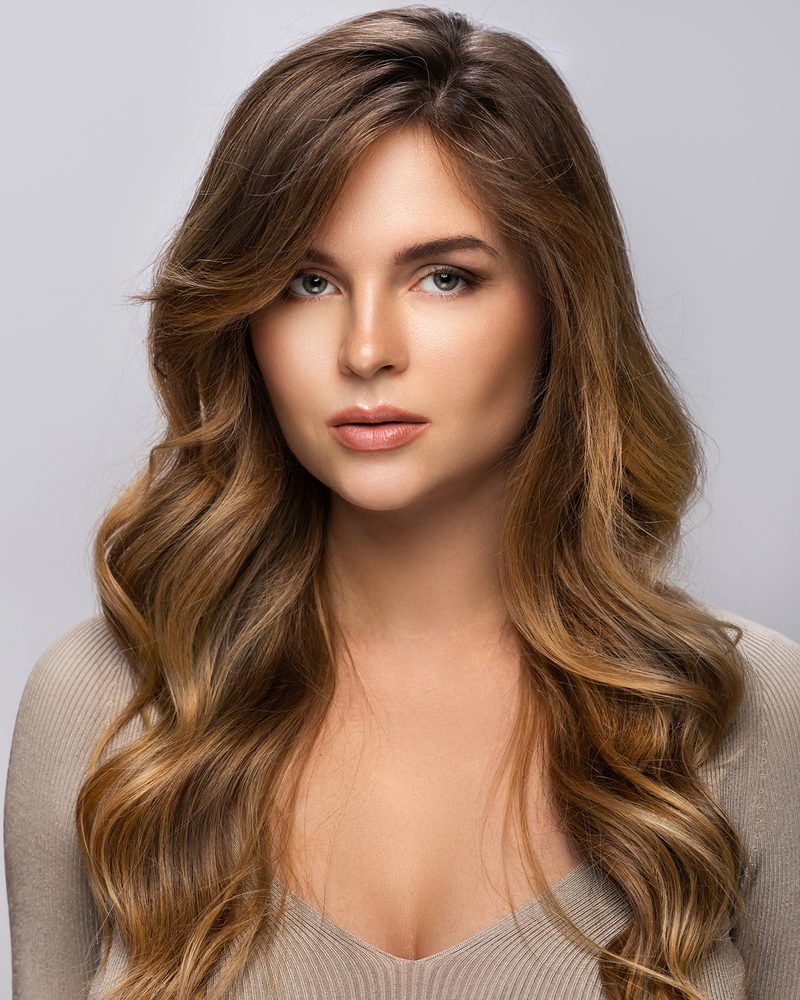 Woman with long, loose brunette waves with soft caramel tones.