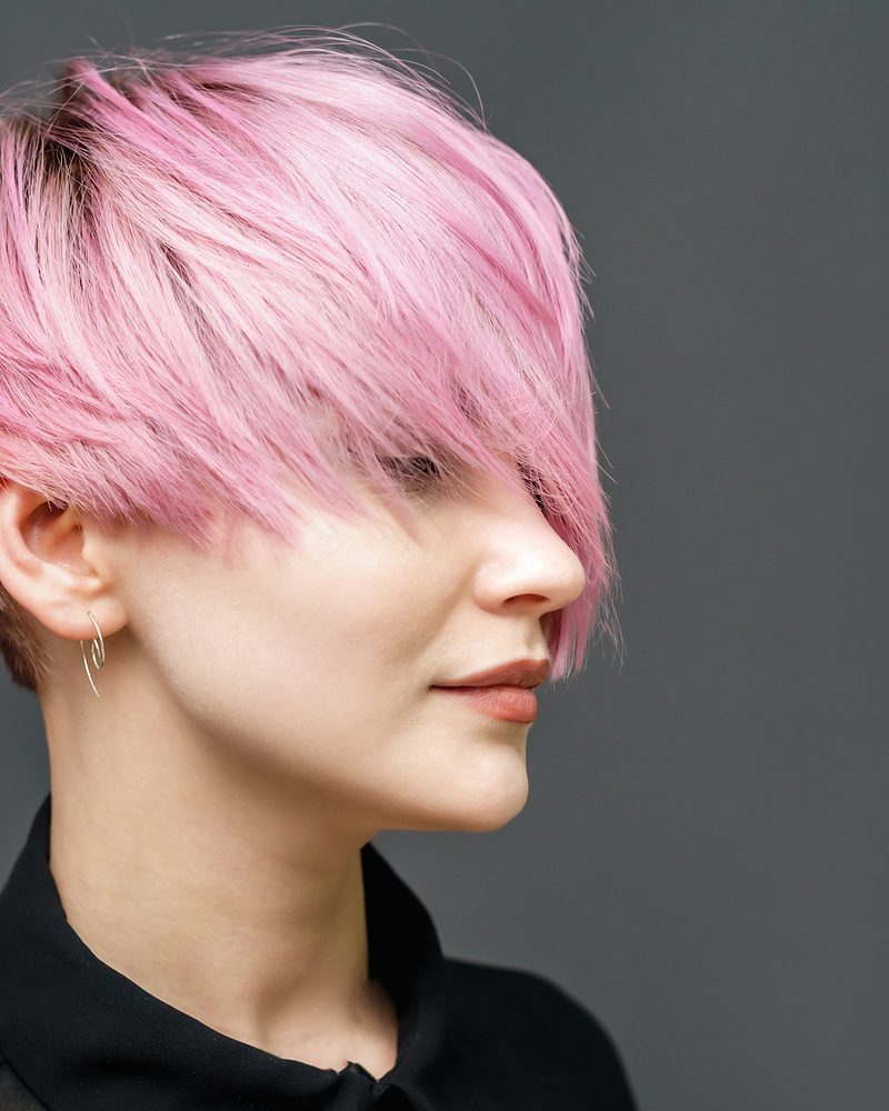 Woman with a short, pastel-pink cut and a long, side-swept fringe.
