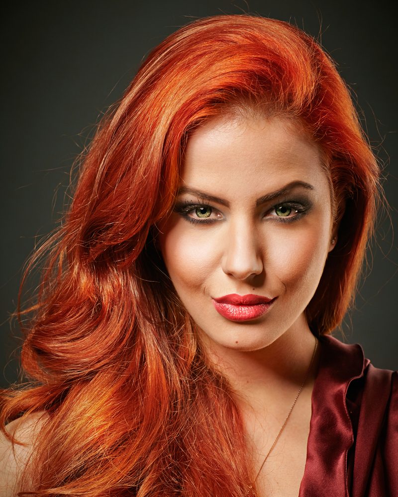 Woman with long, vivid copper-red hair in loose waves.