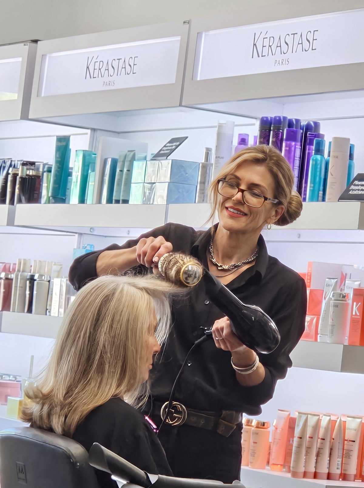 Esther Klein finishing a blow-dry for a client in front of the Kérastase wall, real photo